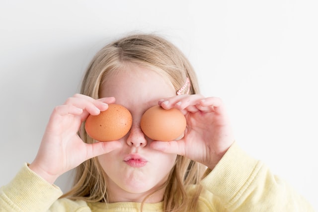 girl holding oranges on her eyes